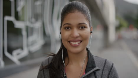 portrait of young woman wearing earphones smiling happy enjoying listening to music in urban city street