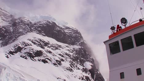 Low-angle-of-an-oceanic-research-vessel-passing-below-high-cliffs-in-Antarctica-1