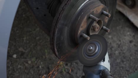 the mechanic cuts the wheel of the car with a grinder