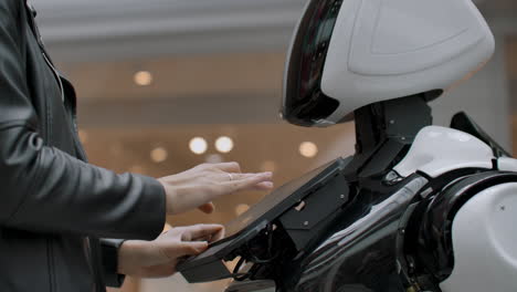 una mujer feliz en contacto con un robot cyborg. haga clic en la pantalla del robot. un droide interactúa con una mujer