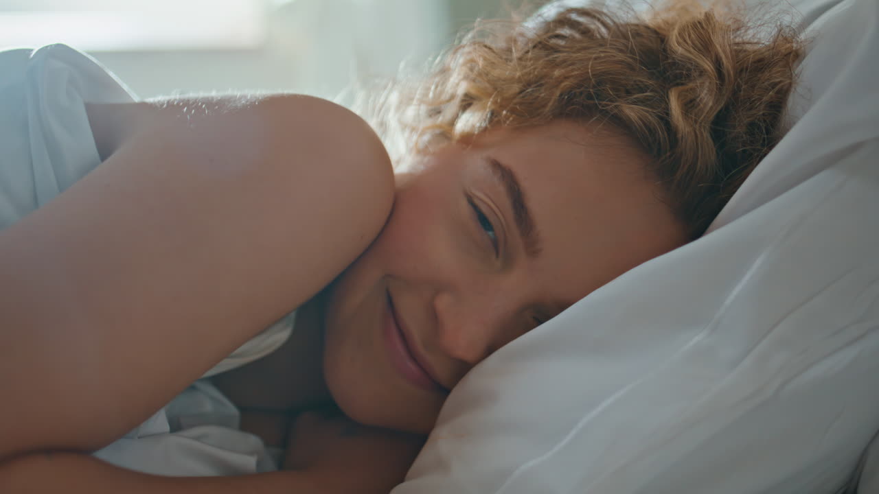 Portrait girl waking up in morning. Sleepy woman opening eyes looking