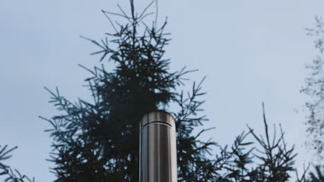 close up of stainless steel chimney with smoke rising from furnace outdoor