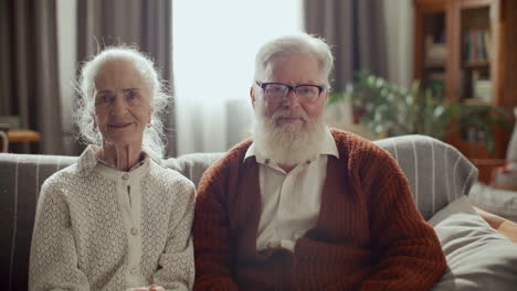 portrait of elderly couple sitting together on couch at home