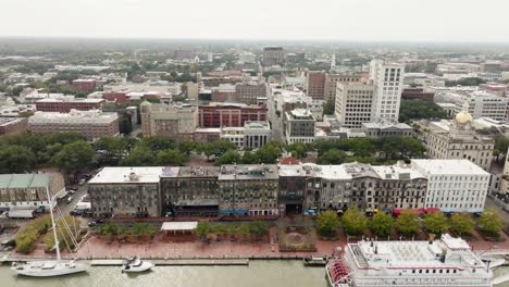 drone of savannah georgia riverfront area along the river with cars and boats on an overcast day approaching city