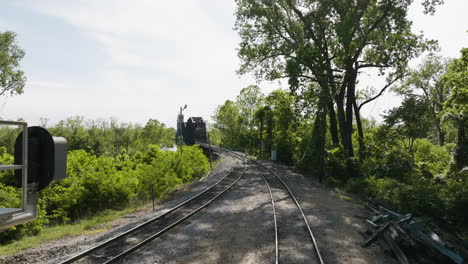 Empty-Rail-Tracks-At-Lee-Creek-Park-Leading-To-Steel-Truss-Bridge-Across-Arkansas-River-In-Van-Buren,-Arkansas