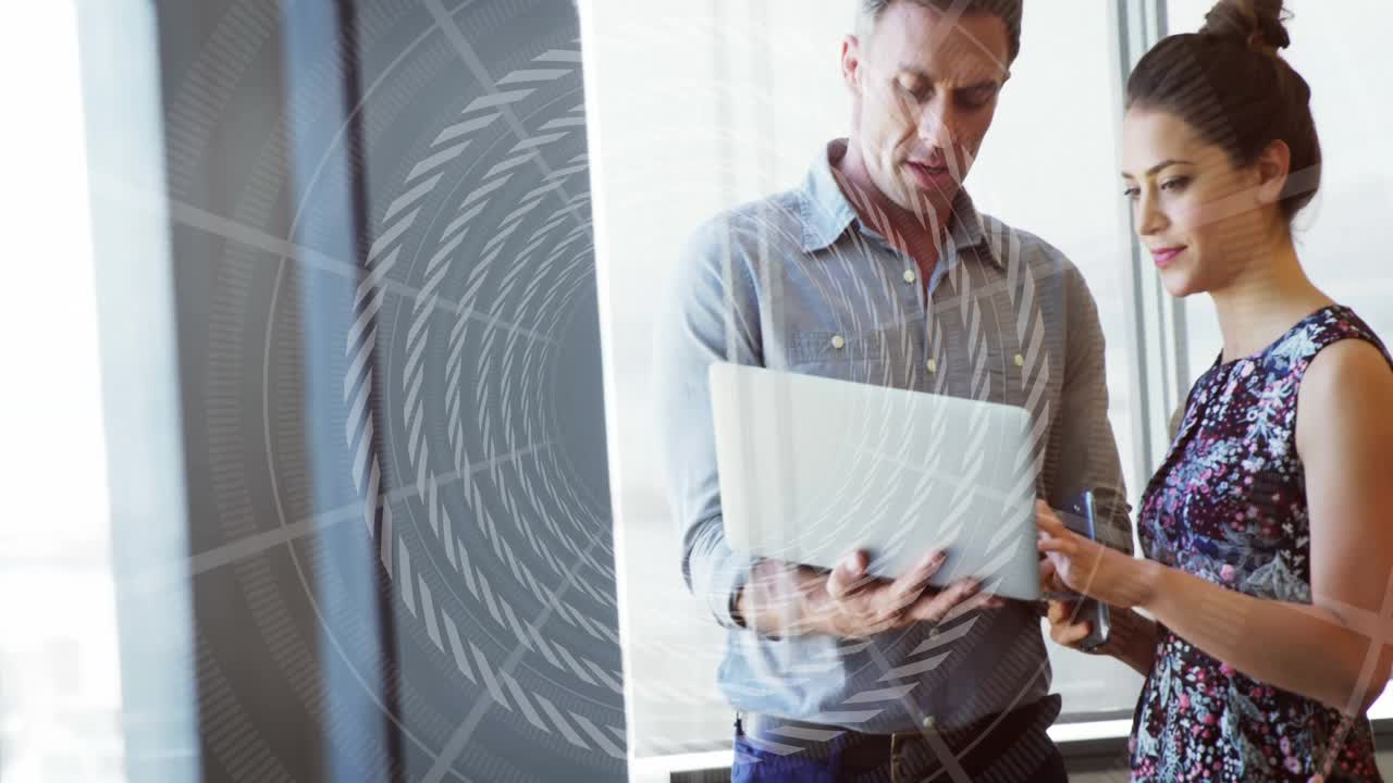 man and woman exploring business data in office using laptop, showing digital graphics on glass