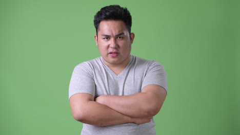 초록색 배경에 젊은 잘생긴 과체중 아시아인