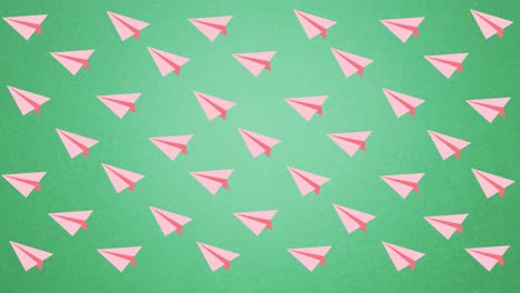digitale animation mehrerer pinkfarbener papierflugzeuge, die gegen einen grünen hintergrund schwimmen