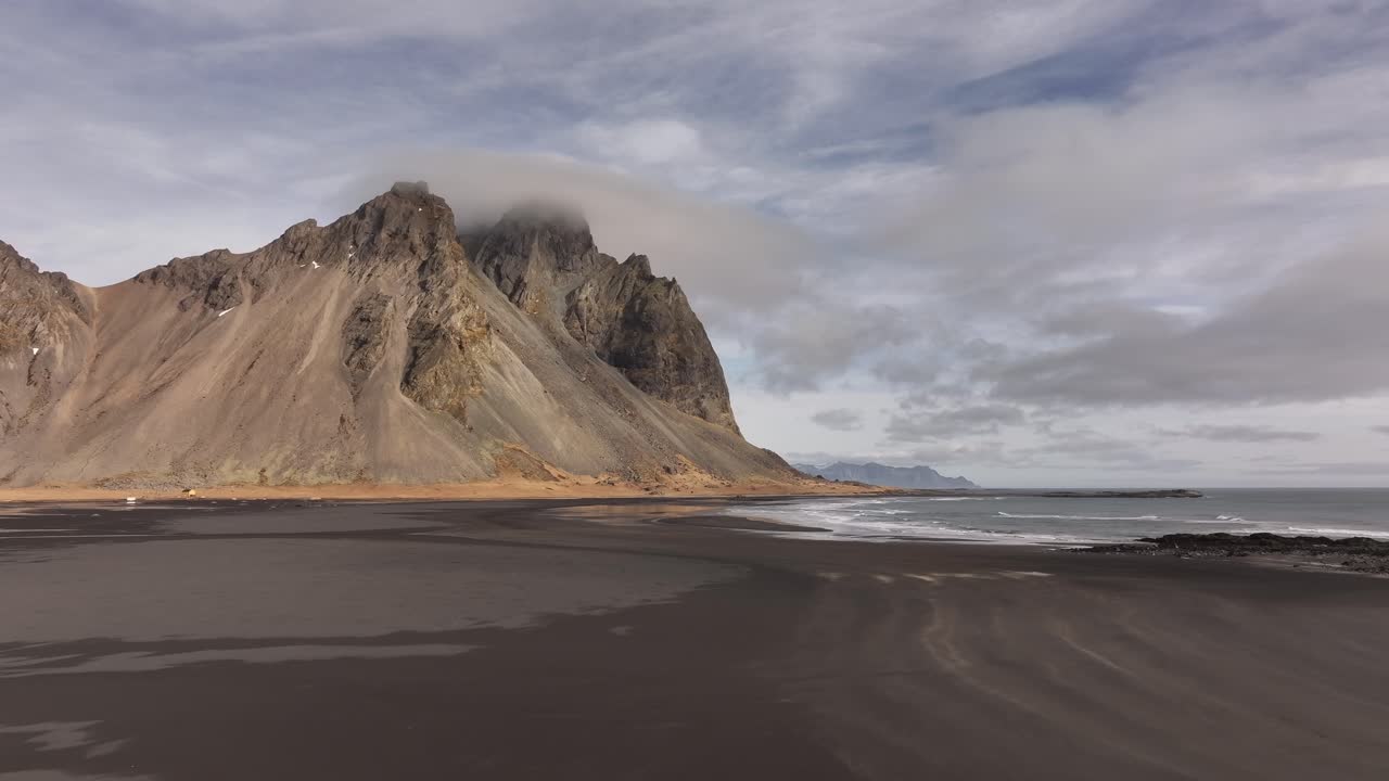 black sand beach stretches beneath Vestrahorn’s cloud-capped summit along Iceland’s rugged coast. Stokksnes, Iceland