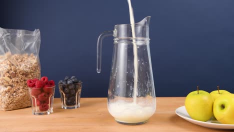 Milk-being-poured-into-a-pitcher,-making-breakfast-cereal