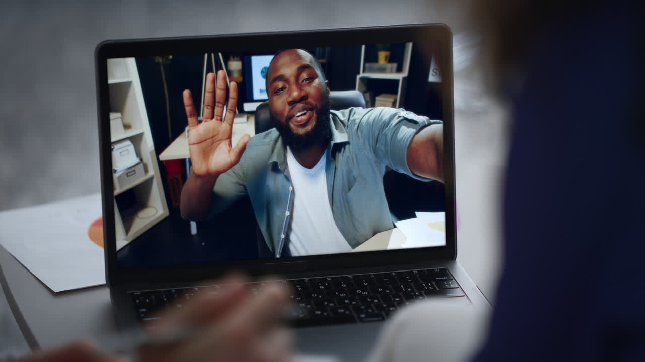 Two people greeting video meeting with colleague by office laptop close up