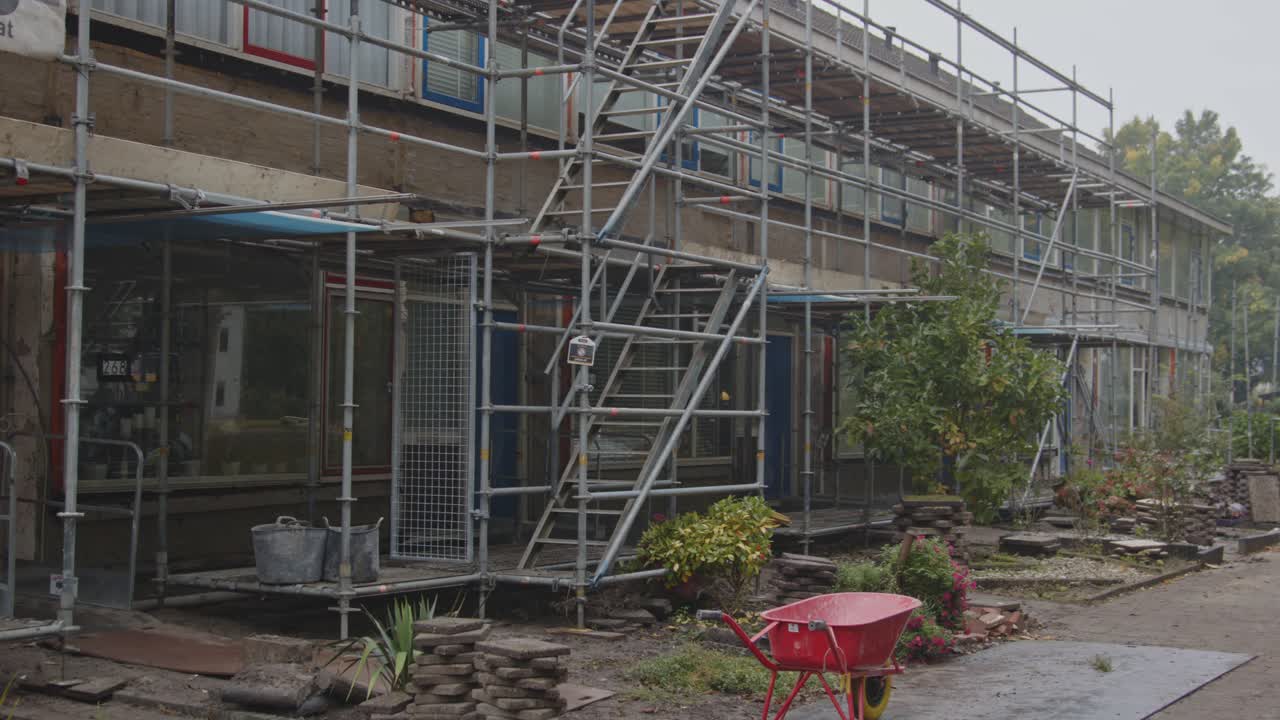 Close pan of scaffolds on the walls of council houses under renovation in the Netherlands