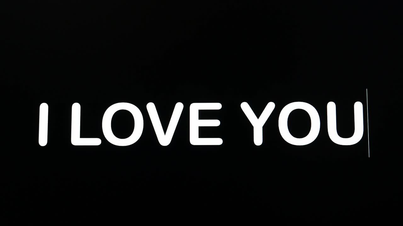 de cerca de i love you siendo escrito en la pantalla del monitor de la computadora con el cursor parpadeante en fondo negro espacio de copia
