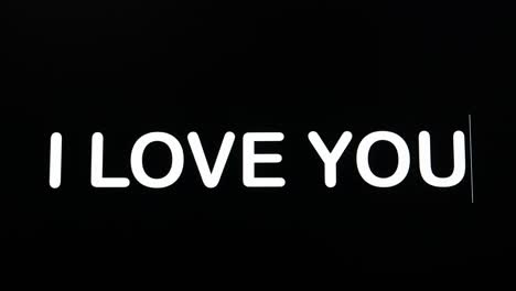 close up of i love you being typed into computer monitor screen with blinking cursor on black background copy space