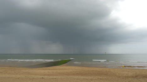 distant rain and thunderstorm over the sea, beach and breakwater view