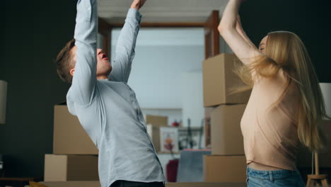 Happy-couple-dancing-housewarming-celebrating-in-own-living-room-full-close-up.