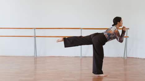 woman practicing ballet poses and balance in a dance studio