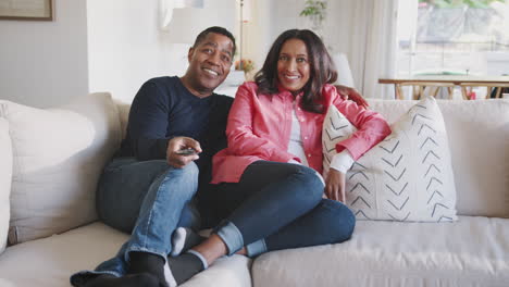 middle aged african american couple reclining on the sofa in their living room watching tv, full length