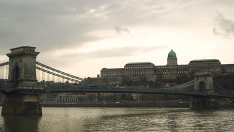 the iconic szechenyi chain bridge spanning over danube river in budapest hungary near the historic buda castle under the cloudy sky - panoramic shot