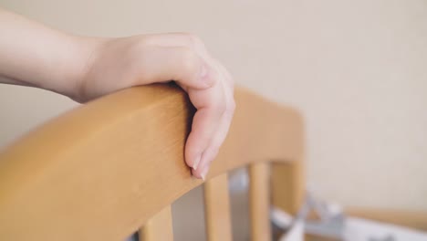 careful-woman-rocks-baby-bed-by-hand-in-children-room