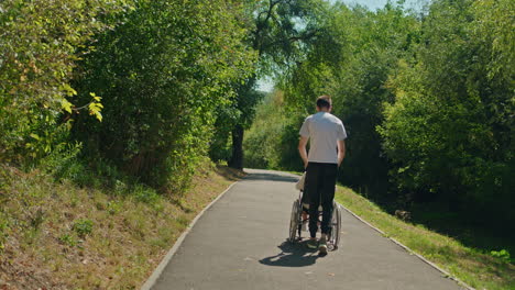 man pushing wheelchair in park