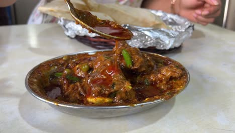 close-up of a rich curry dish being served with bread