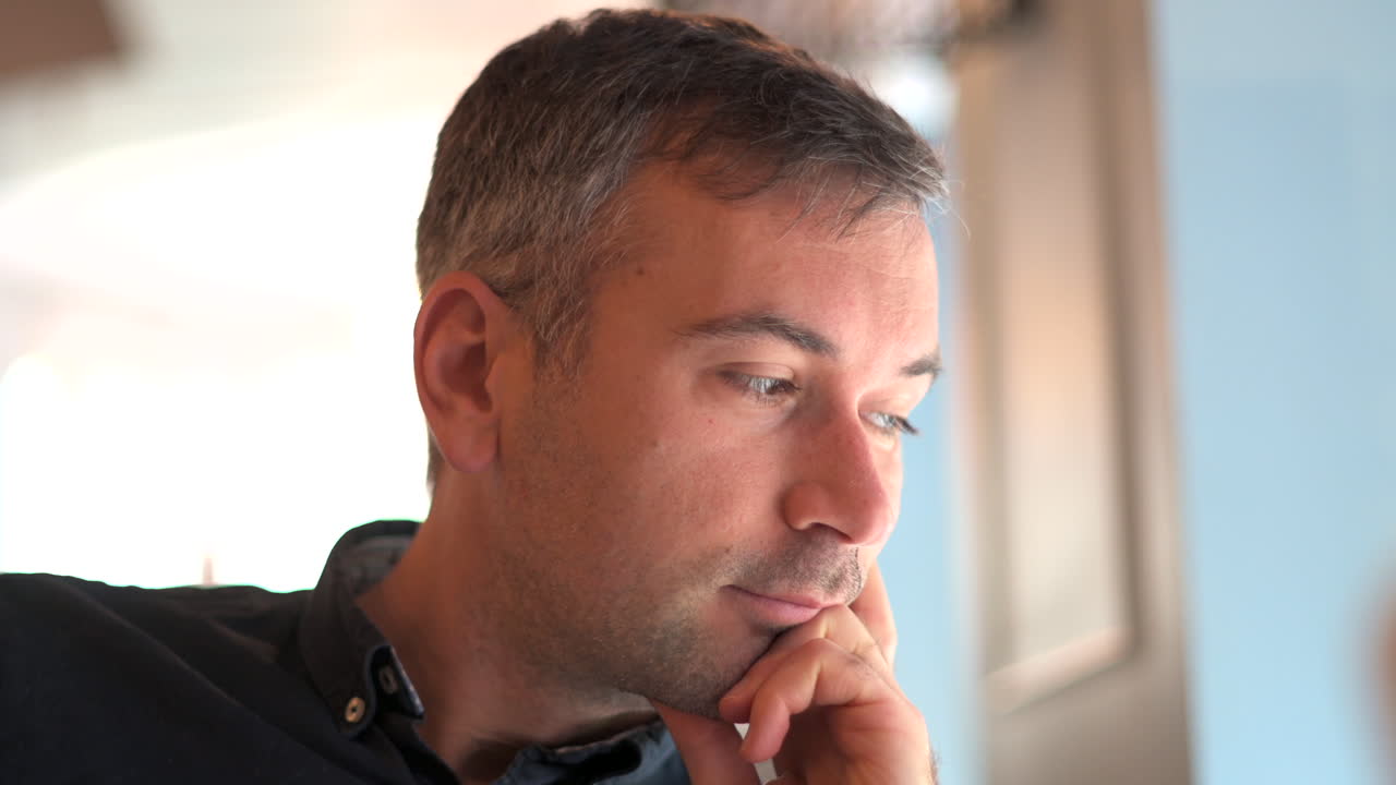 Man in dark blue shirt looking out the window at a restaurant