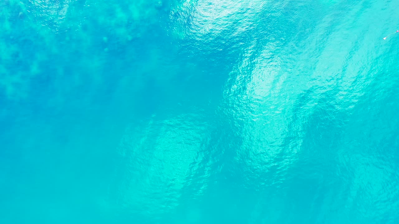 터크와 카이코스의 유리 표면에 햇빛을 반사하는 석호의 크리스탈 에메랄드 물 아래 산호초와 평화로운 바다 질감