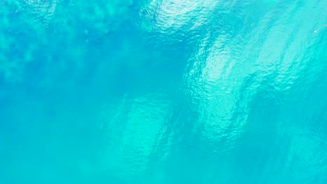 peaceful sea texture with coral reefs under crystal emerald water of lagoon reflecting sunlight on glassy surface in turks and caicos