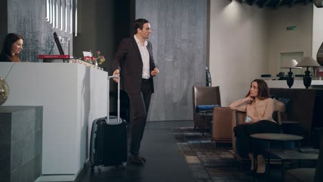 businessman taking room key at hotel reception. traveling couple settling hotel