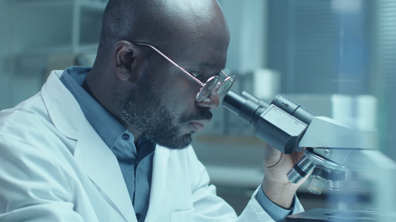 Medico afroamericano che esegue un test medico con microscopio in laboratorio