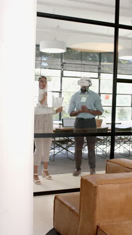 vertical video: using vr headset, colleagues discussing project in modern office setting