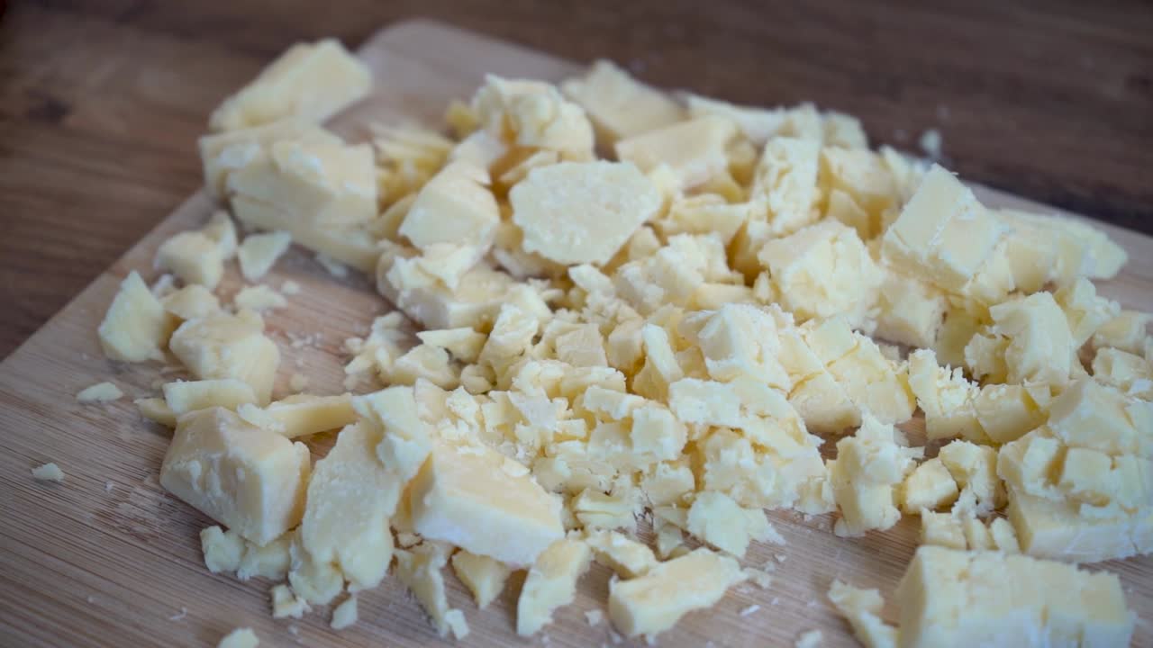 primer plano de queso picado en una tabla de cortar de madera