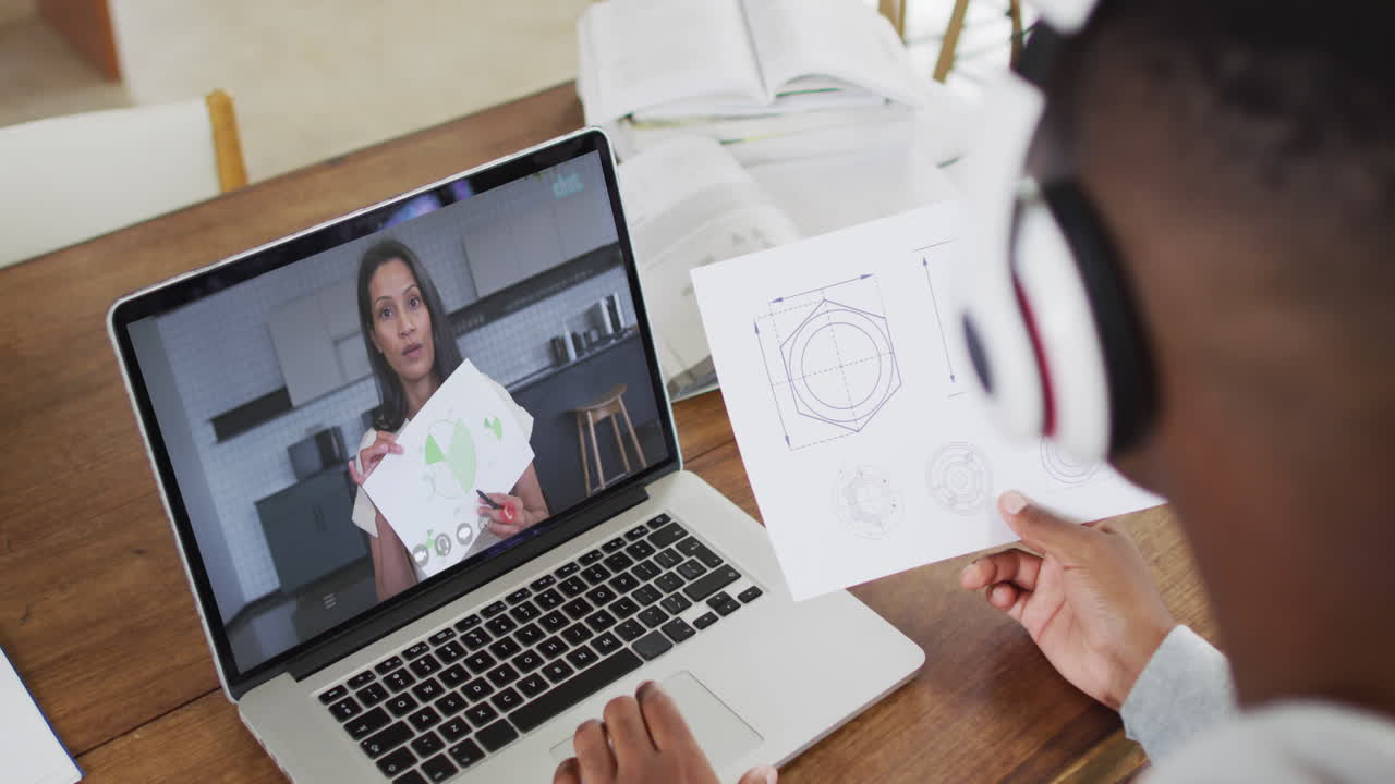 hombre de negocios afroamericano sentado en un escritorio usando una computadora portátil haciendo una videollamada con una colega