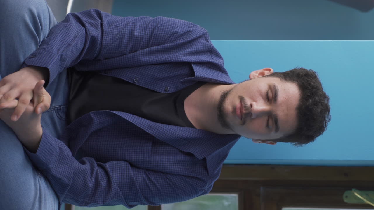 지상에 앉아 있는 남자가 울고 있는 수직 영상입니다.