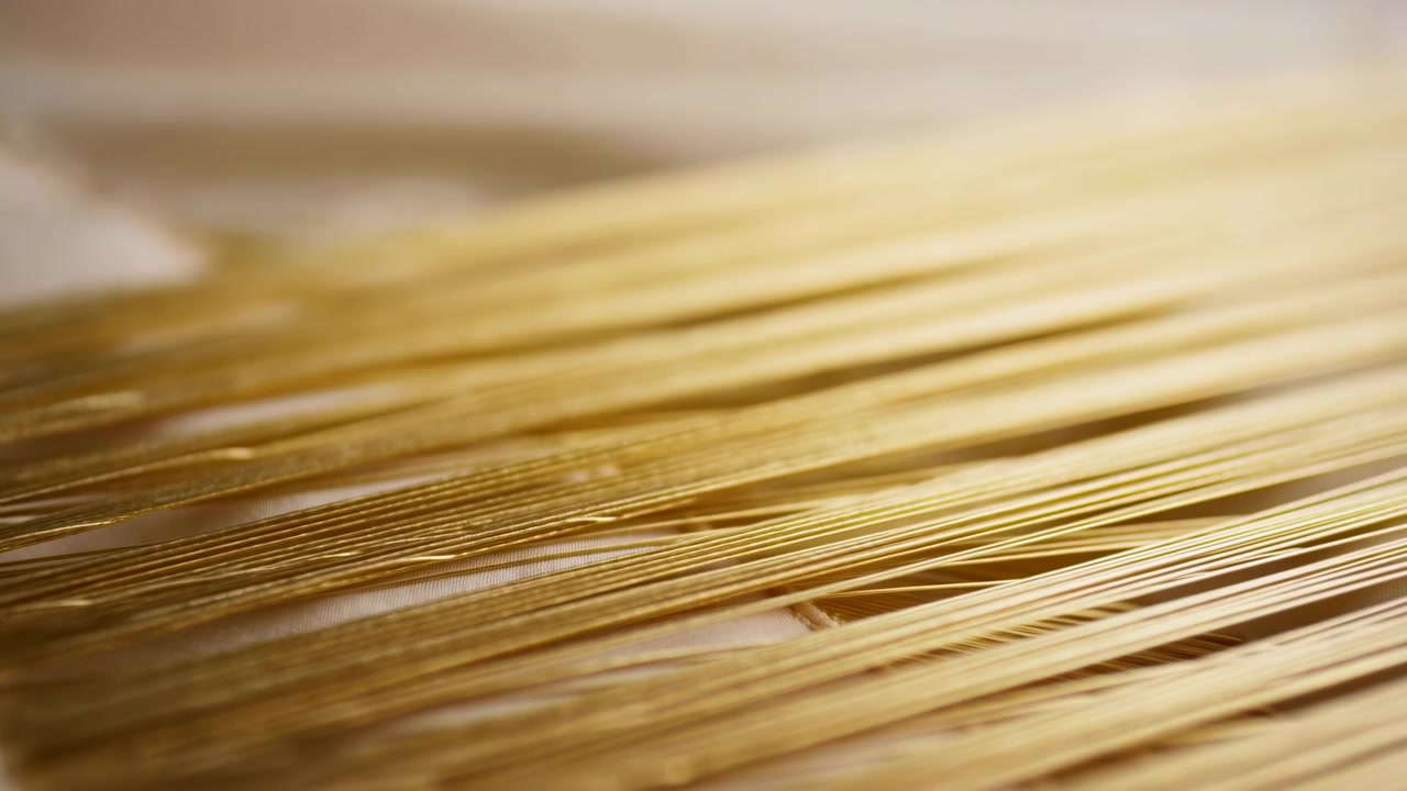 Vista obliqua bassa che mostra sottili fogli di lamina d'oro disposti in file orizzontali impilate, con un leggero spostamento laterale, messa a fuoco a profondità di campo ridotta, sfocatura morbida e una lucentezza metallica luminosa, con oro, lamina, foglio.