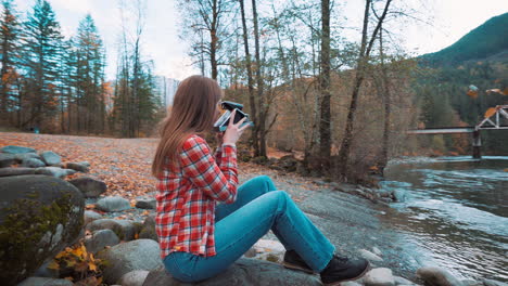 Eine-Fotografin-Macht-Ein-Polaroidfoto-Am-Flussufer-Inmitten-Der-Herbstfarben