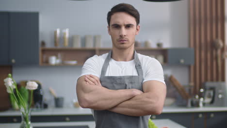 serious chef male looking camera at home kitchen. man crossing hands indoors.