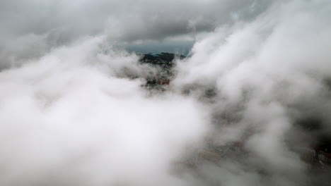 aerial hyperlapse above sapa city, vietnam, with moving swirling clouds over mountain peaks and terraced fields with city buildings gradually appearing and disappearing