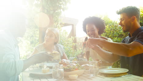 group of smiling multi-cultural friends outdoors at home eating meal together