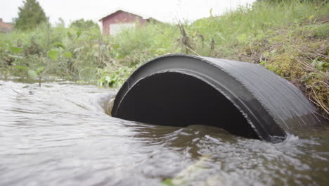 la escorrentía de agua de lluvia fluye hacia una gran tubería de drenaje negra en el campo