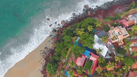 Vista-Aérea-De-Arriba-Hacia-Abajo-Sobre-El-Paisaje-Marino-Con-Olas-Tranquilas-Golpeando-Los-Acantilados-Con-Resorts-Y-Restaurantes-Frente-Al-Mar