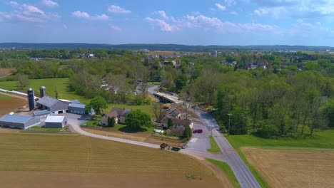 aerial view of farmlands and a bridge being replaced over a stream with an amish farmer doing is work on a beautiful sunny day