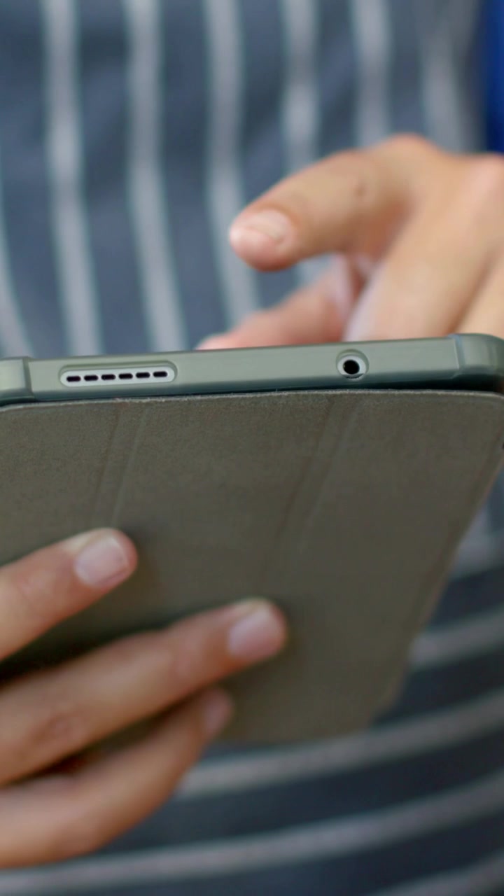 Vertical video: Swiping tablet with hands, right finger entering and viewing recipe outdoors, apron