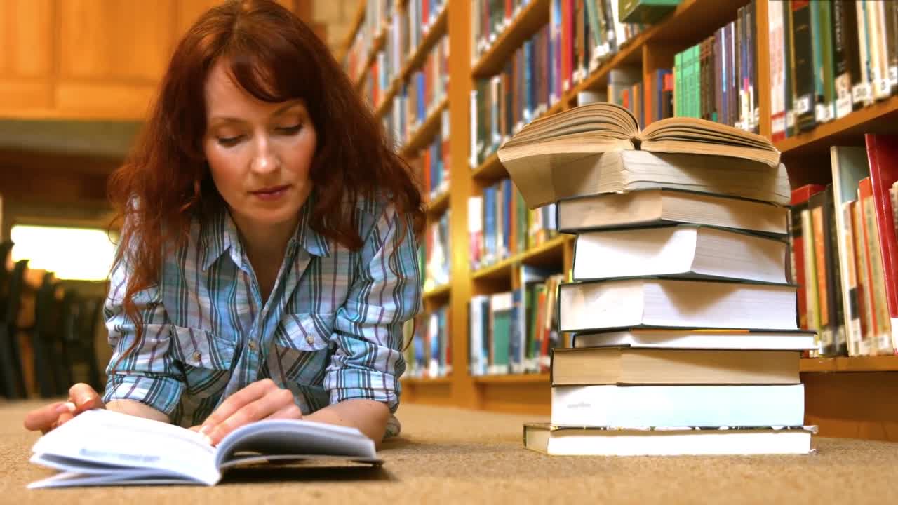 estudiante leyendo un libro de la biblioteca