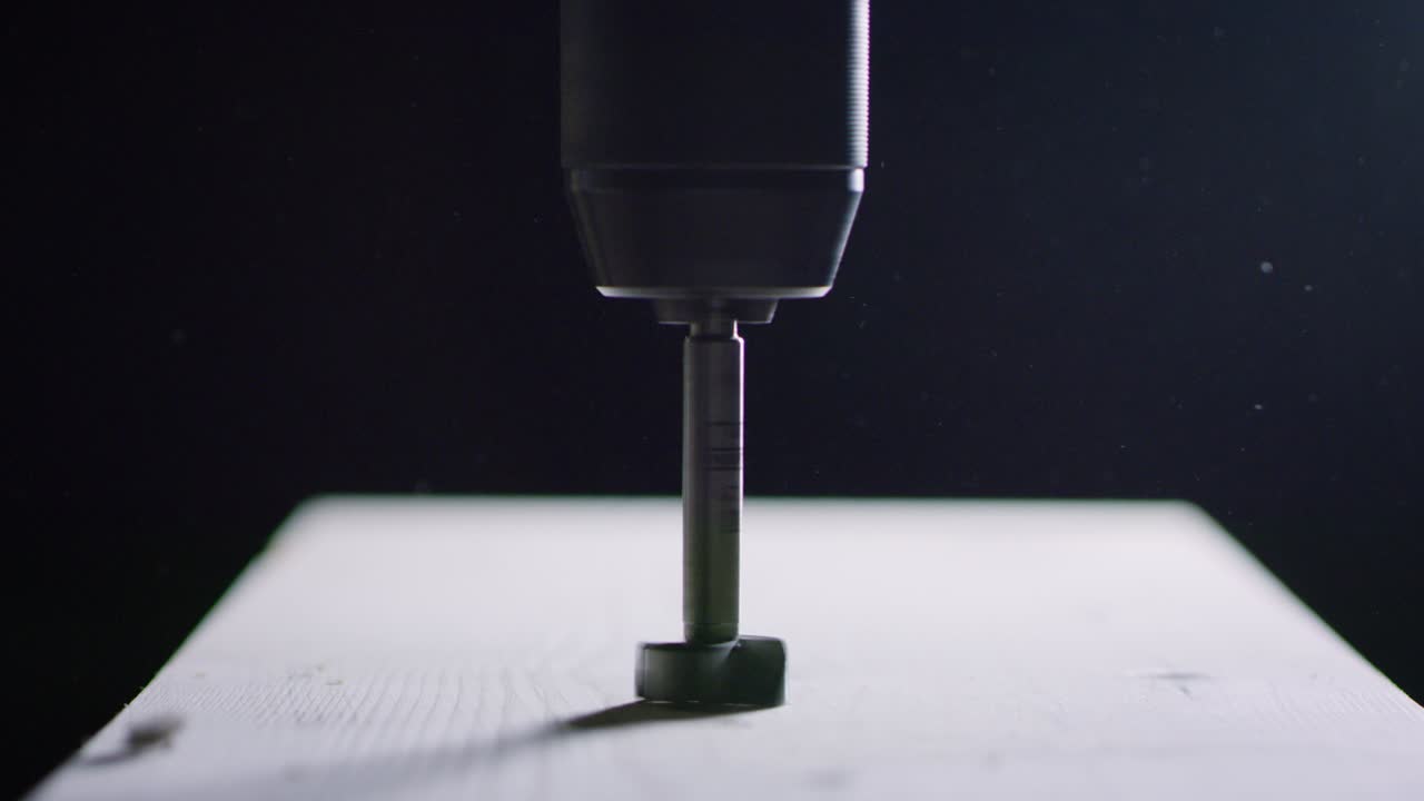 나무 공장의 작업실에서 드릴 머신으로 목재를 작업하는 전문 목공의 매크로 클로즈업.