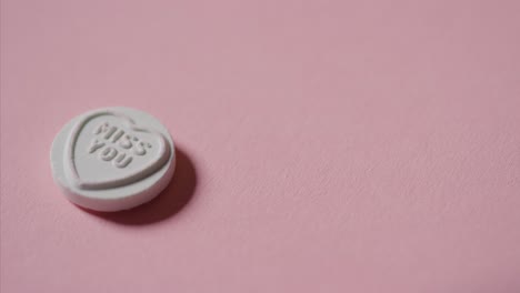 mano recogiendo dulces de corazón con un mensaje romántico te extraño en el fondo rosa