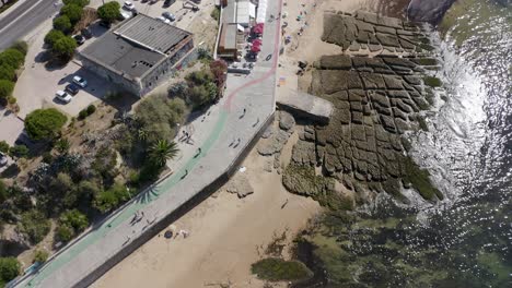 Aerial-rising,-drone-shot-over-the-sea,-revealing-the-Praia-da-Poca-Beach,-on-a-warm-sunny-day,-in-Estoril,-Lisbon,-Portugal