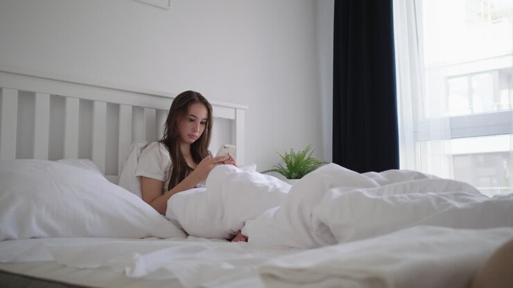 Kvinde bruger telefon i sengen