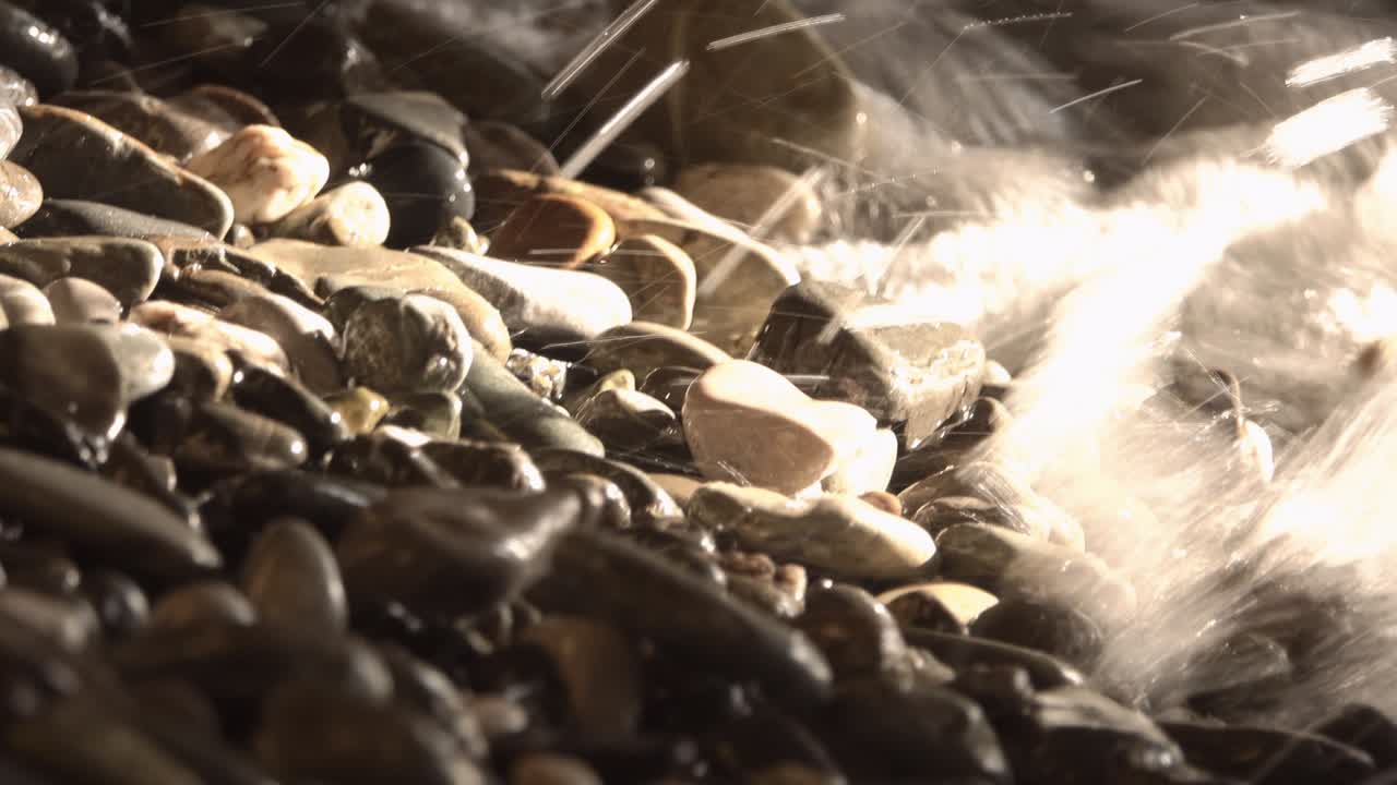 바다의 바위, 작은 돌의 질감, 바다의 파도에서 빛의 광선.